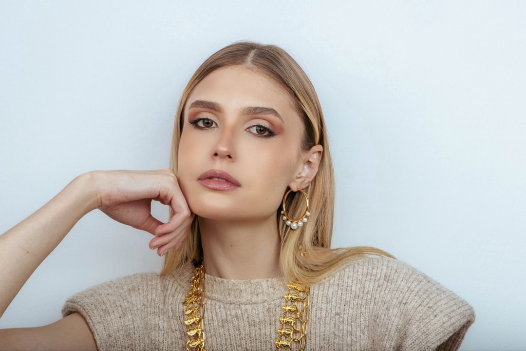 Model wearing gold earrings with a pastel top